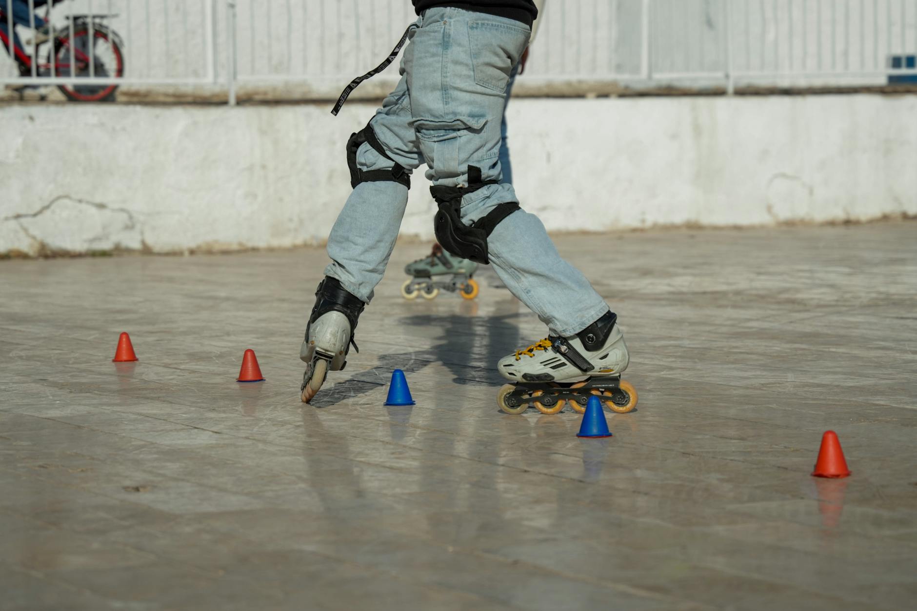 Mężczyzna ćwiczy slalom na rolkach między pachołkami w parku