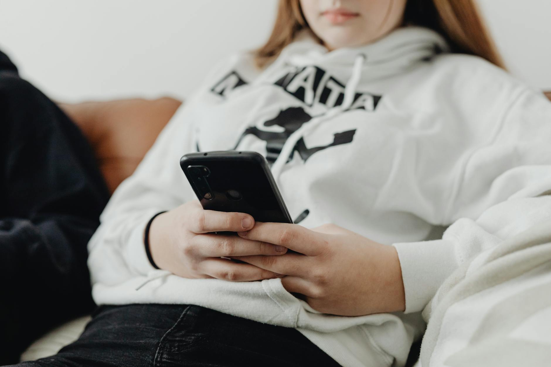 Radykalizacja młodzieży w internecie: jak rozpoznać wczesne sygnały zagrożenia terroryzmem Nastolatka w białej bluzie z kapturem wpatrzona w ekran smartfona