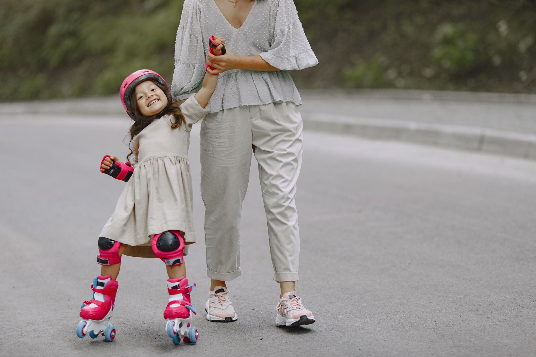 Mama pomaga córce uczyć się jazdy na rolkach na asfaltowej ścieżce
